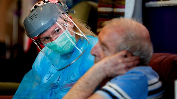 A nurse in personal protective equipment speaks to a resident at a care home in Nottingham. 