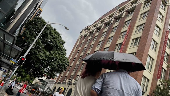 A couple huddle under an umbrella in a rainy Brisbane CBD as severe storms descend on south-east Queensland.