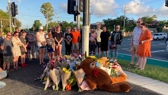 Danielle Leadbetter (far right in the orange dress) looks on as tributes accumulate.