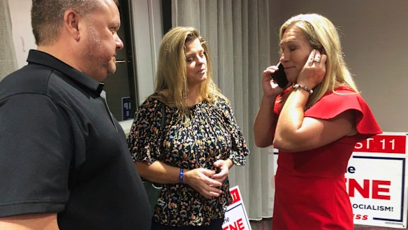 Supporters stand with construction executive Marjorie Taylor Greene, right, as she's on the phone in Rome, Georgia. 