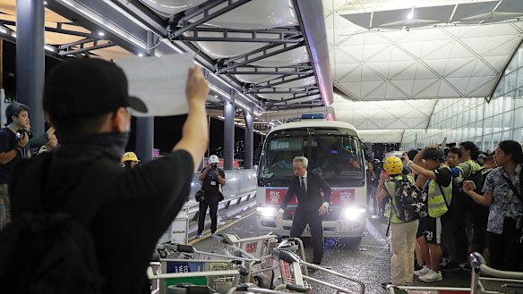 Protesters use luggage trolleys to block a police van at the airport.