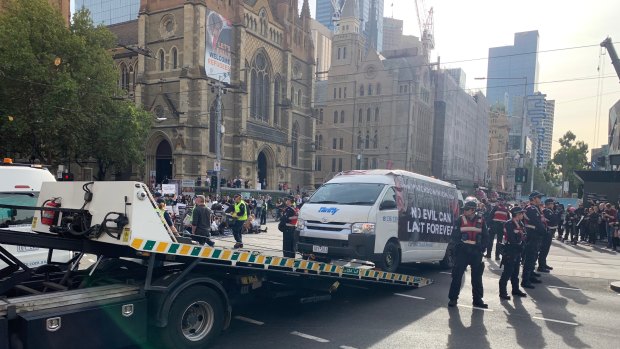 The vans, which had been parked in the middle of the intersection, are being towed. 