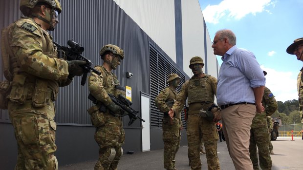 Scott Morrison meets ADF personnel at the Redbank military vehicle centre on Sunday, but Deb Frecklington was nowhere to be seen. 