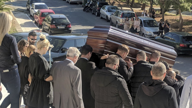 The coffin of John Macris leaves a church in Athens, with widow Viktoria Karyda following.