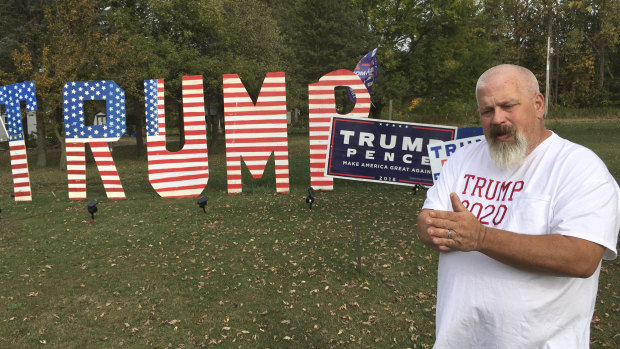 Mike Devore poses near a sign he made to show his support for President Donald Trump in Wayne, Ohio.