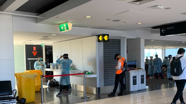 Authorities wait for the arrival of a Brisbane flight at Melbourne Airport on Saturday.