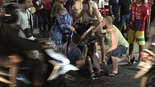 A girl is tended to by her friends on the side of the road after she was accidentally hit, causing a fight to break out between a group of Australians. 