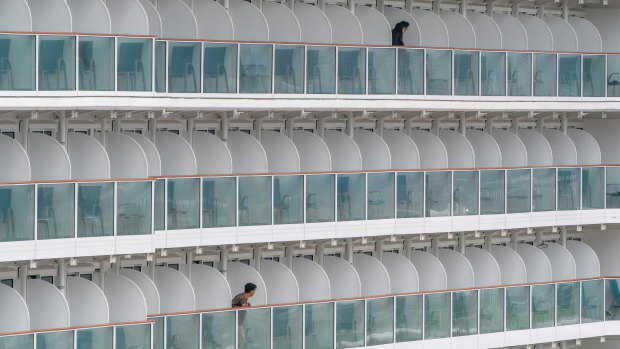 Passengers stand on balconies aboard The World Dream cruise ship as it sits moored at Kai Tak Cruise Terminal in Hong Kong, China. 