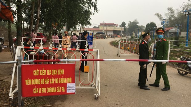Police wearing masks guard a road checkpoint before entering the Son Loi commune in Vinh Phuc province, Vietnam.