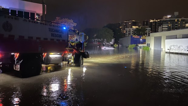 Swiftwater rescue crews check a floating car in Lotus Street, Woolloongabba, on Wednesday night to ensure nobody is inside.