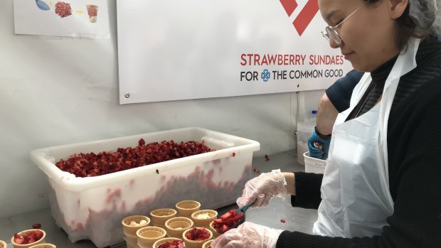 A volunteer struggles to keep up with demand for the icy strawberry treats.