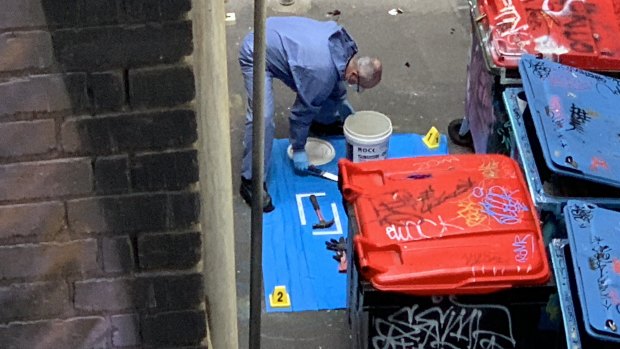Forensics officers remove the contents of a white bucket. Inside was a hammer, 25cm kitchen knife, scissors, multiple pairs of gloves, a orange hi-vis jacket and a newspaper possibly linked to the fugitive. Laid out on blue plastic for forensic examination, the items were photographed before being placed into paper bags.