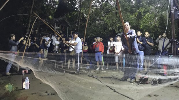 Relatives hold fishing nets, as a symbol to fish out lost spirits inside cave, as a group of locals and relatives perform a ritual calling for those are missing at the entrance of the cave on Tuesday.