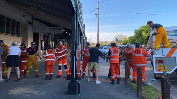 SES and CFA volunteers form a human chain as they help lay sandbags at The Black Pudding Cafe.