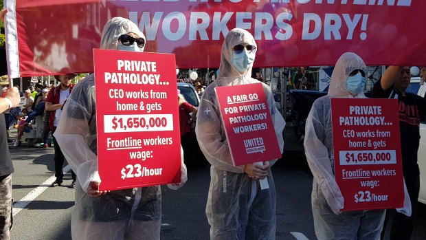 Pathology staff don hazmat suits for the Labour Day march in Brisbane.