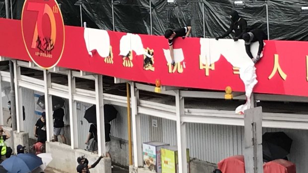 Protesters tear down a newly erected red banner celebrating the 70th anniversary of Communist China.