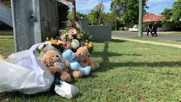 Floral tributes and teddy bears placed near the scene.