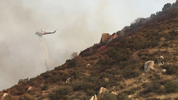 A helicopter makes a water drop on a brush fire in Reche Canyon, California.