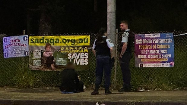 Police guard a man in handcuffs near the scene of Sunday night’s shooting
 
