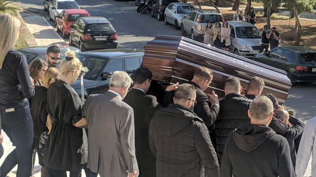 John Macris' coffin leaves the church, with widow Viktoria Karyda following.