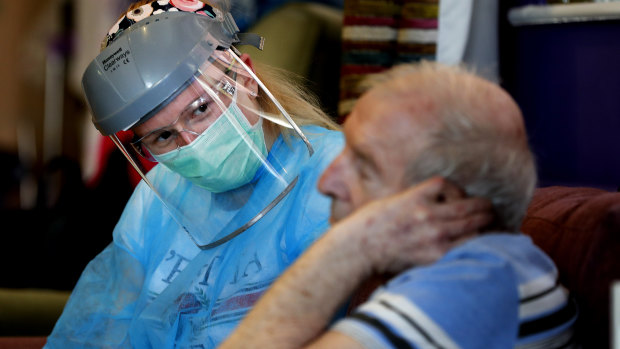 A nurse in personal protective equipment speaks to a resident at a care home in Nottingham. 