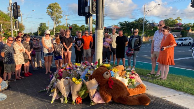 Danielle Leadbetter (far right in the orange dress) looks on as tributes accumulate.