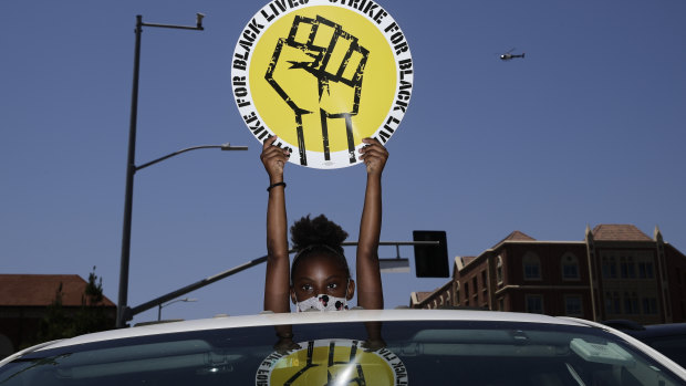Audrey Reed, 8, holds up a sign  during a rally in Los Angeles in July. Thousands of workers across the country walked off the job to protest against systemic racism and economic inequality, which they say has worsened during the coronavirus pandemic. 