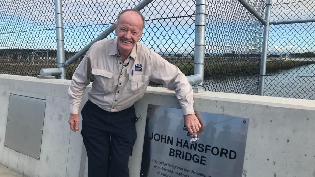 Retiring Brisbane Airport worker John Hansford polishes a sign of his eponymous bridge, commemorating his five decades on the job.