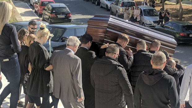 The coffin of John Macris leaves the church, with widow Viktoria Karyda following.
