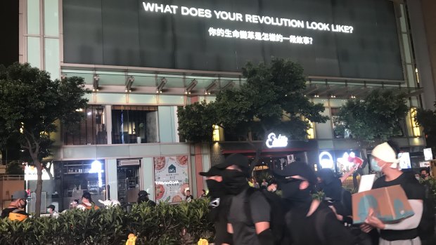 Hong Kong protesters walk past a sign on Nathan Road that reads 'What does your revolution look like?'.
