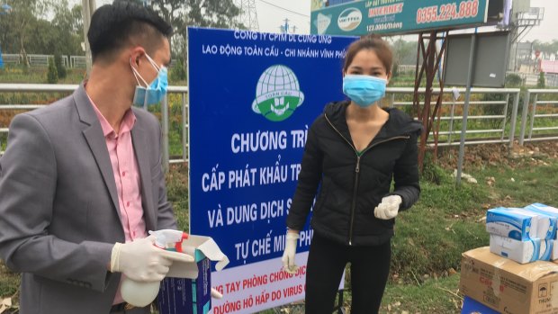 Officials stand in front of a warning sign about the COVID-19 disease outside Son Loi commune in Vinh Phuc province, Vietnam.