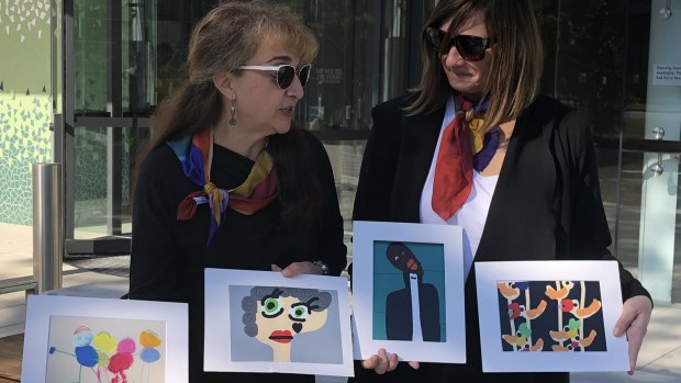 Sarina Marchi and Peta Rostirola, friends of Maria Lutz, displaying Elisa and Martin's artworks outside the Coroners Court in Lidcombe.