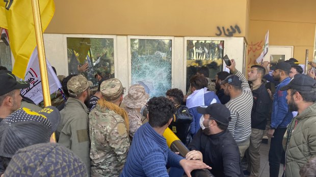 Protesters smash a window inside the US embassy compound, in Baghdad, on December 31.