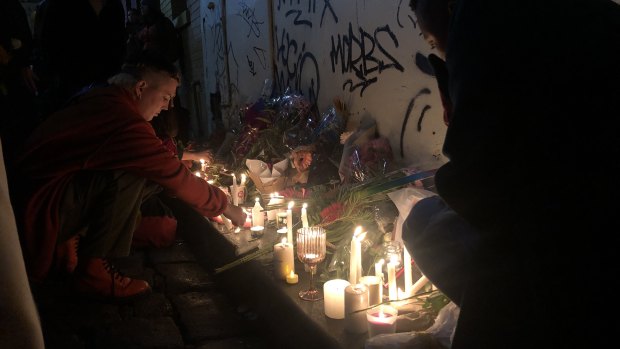 A mourner lights a candle in Celestial Avenue in Chinatown, following the vigil at Federation Square.