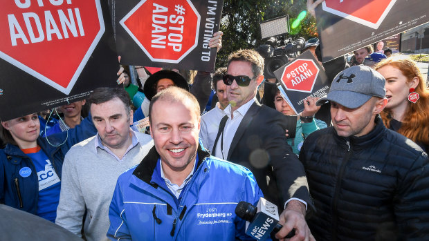 Treasurer Josh Frydenberg voting at Balwyn North Primary School surrounded by protesters carrying 'Stop Adani' placards
