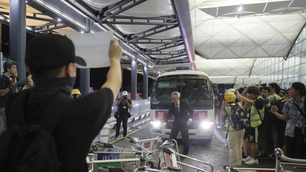 Protesters use luggage trolleys to block a police van at the airport.