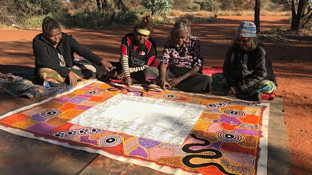 Lead artist Rene Kulitja (third from left) supervises artists Christine Brumby, Charmaine Kulitja and Happy Reid. 