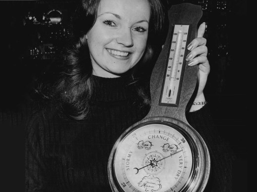 Frances Hewitt with a thermometer showing the Fahrenheit reading on the left side  and Celsius on the right.