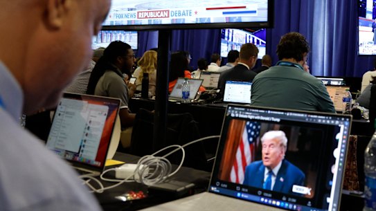 A reporter watches Donald Trump’s online interview with Tucker Carlson during the first Republican candidates’ debate for the 2024 election.