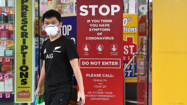A customer wearing a protective face mask leaving a pharmacy.