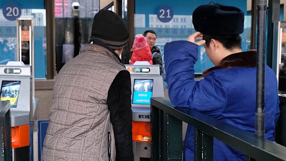 Train travellers are confronted by a new facial recognition system as they travel home from Beijing for Chinese New Year. 