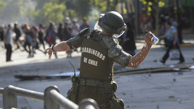 A Chilean police officer throws a tear gas grenade to demonstrators in Santiago on Wednesday. Prosecutors want police investigated for human rights abuses.