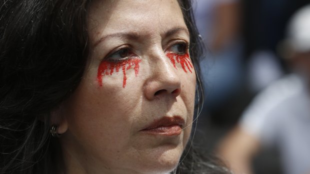 A woman with her eyes painting with red tears participates in an opposition protest against torture and President Nicolas Maduro in Caracas on Venezuela's Independence Day.
