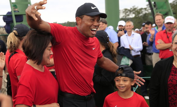 Family affair: Tiger Woods, in his  Sunday-best red and black,  with son Charlie. 