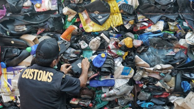 Indonesian customs official examines Australia's contaminated plastic waste at Batam port.
