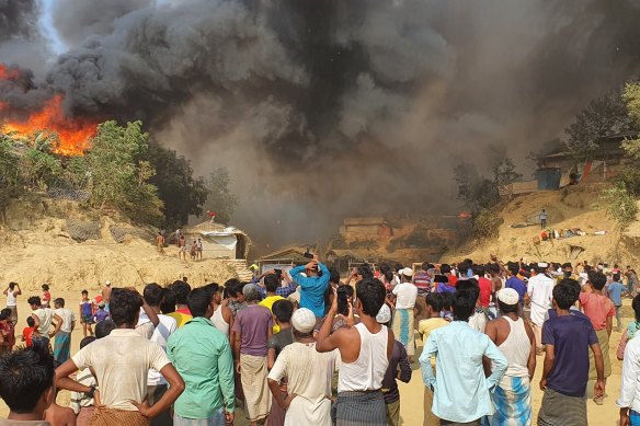 Rohingya refugees watch a fire destroy their camp in southern Bangladesh on Monday.