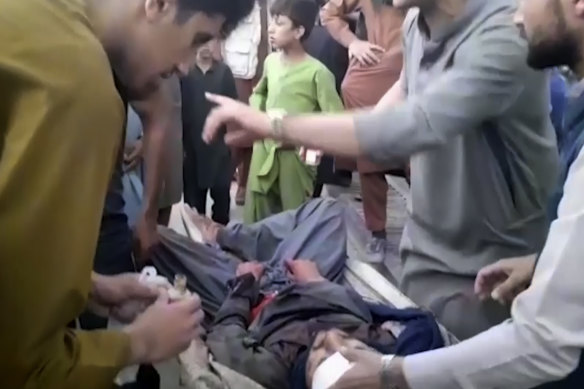 People try to help a wounded man near the site of one of the bombings outside Kabul airport.