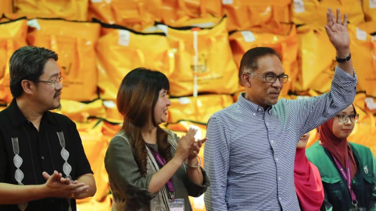 Malaysia's 'premier-in-waiting'  Anwar Ibrahim, right, waves as he celebrates after winning the by-election in the southern coastal town in Port Dickson, Malaysia. on Saturday.