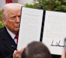 Donald Trump holds a signed executive order during an event to announce new tariffs in the Rose Garden of the White House.