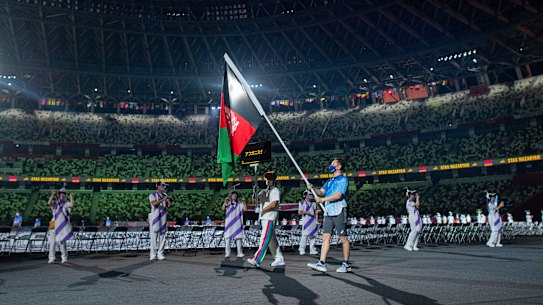 A Paralympic volunteer carries the national flag of Afghanistan during the athlete’s parade.
